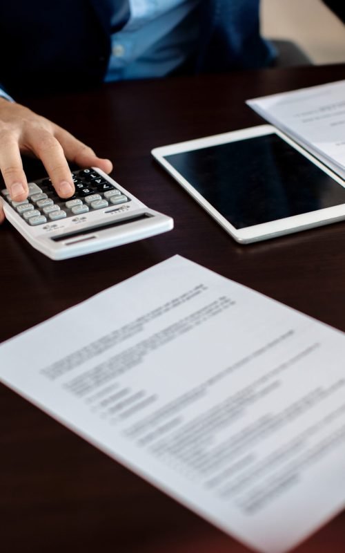 Close-up of real estate agent calculating costs of a mortgage agreement while having a meeting with a client in the office.